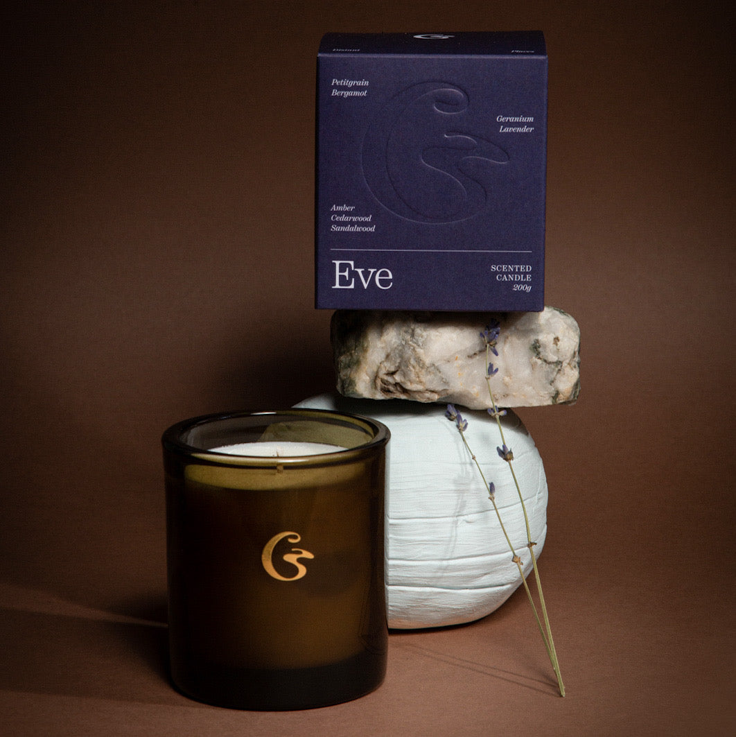 Amber candle jar with some moon shaped rocks and a purple box which says Eve