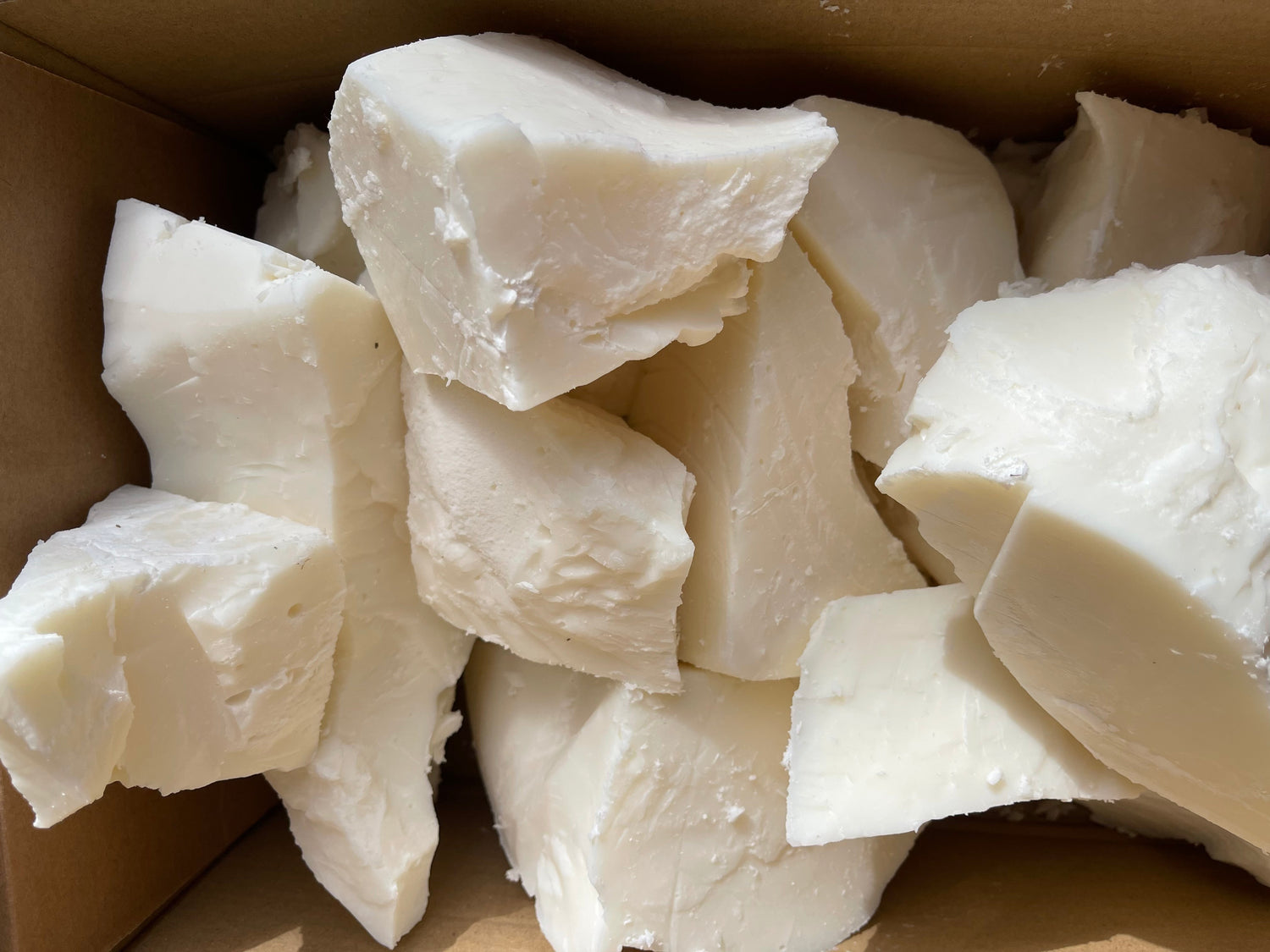Chunks of white rapeseed and coconut wax in a brown box. 