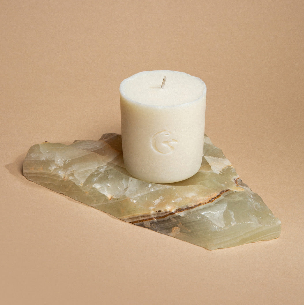 A wax candle refill block with the cedar logo embossed on it. It is sat on a piece of marble
