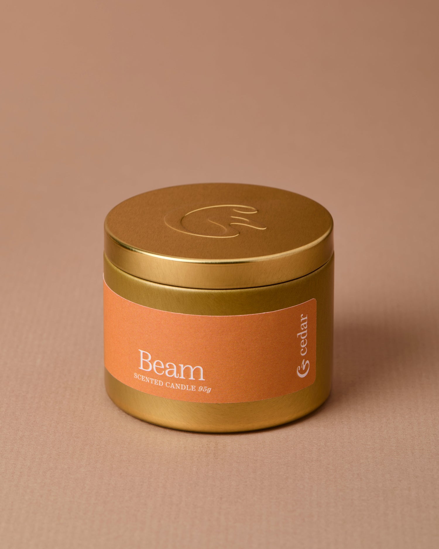 A gold tin candle with an orange label that says beam