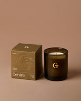 Dark glass candle with a matching box on a brown background, featuring the &
