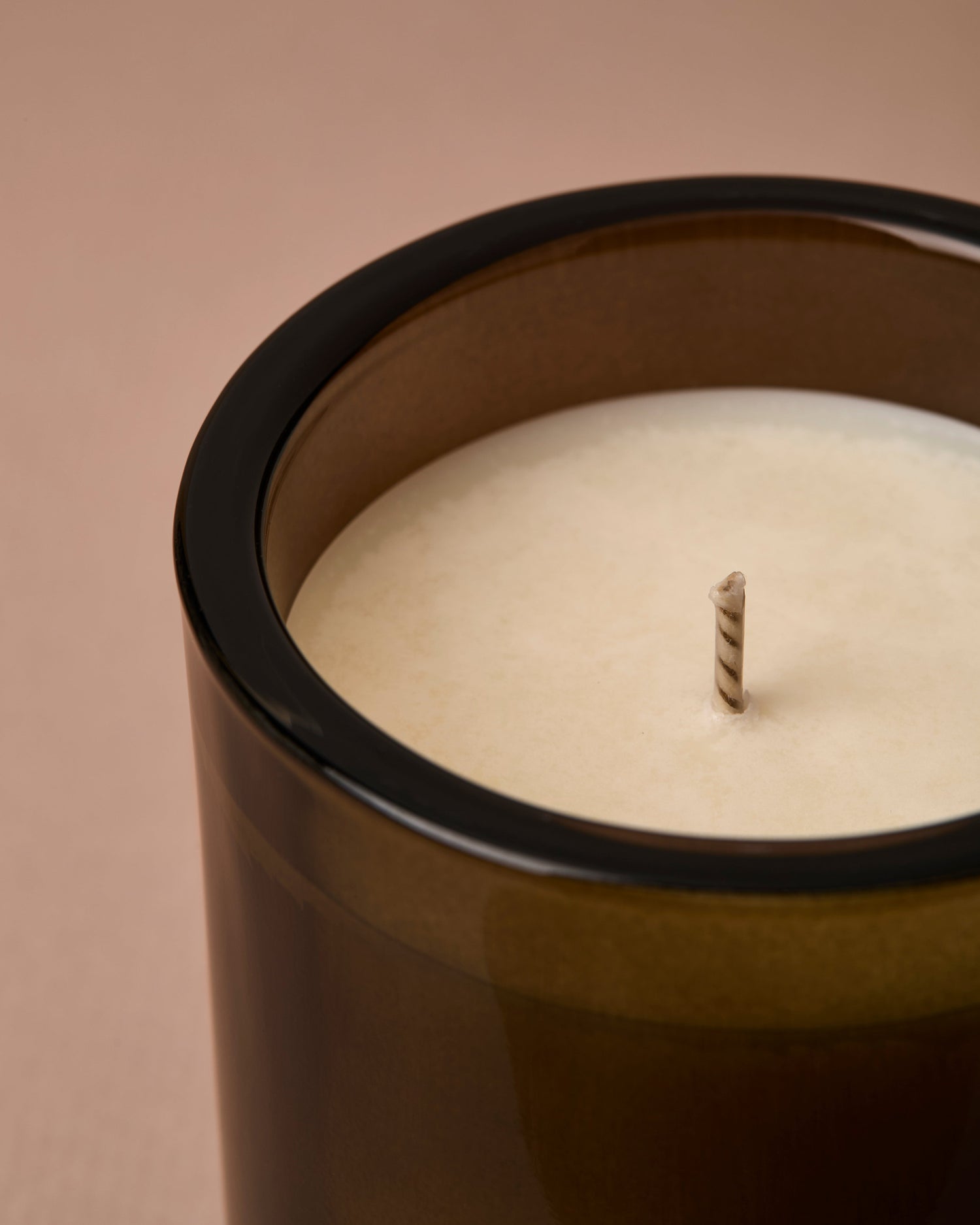Candle in a green/brown container on a beige background