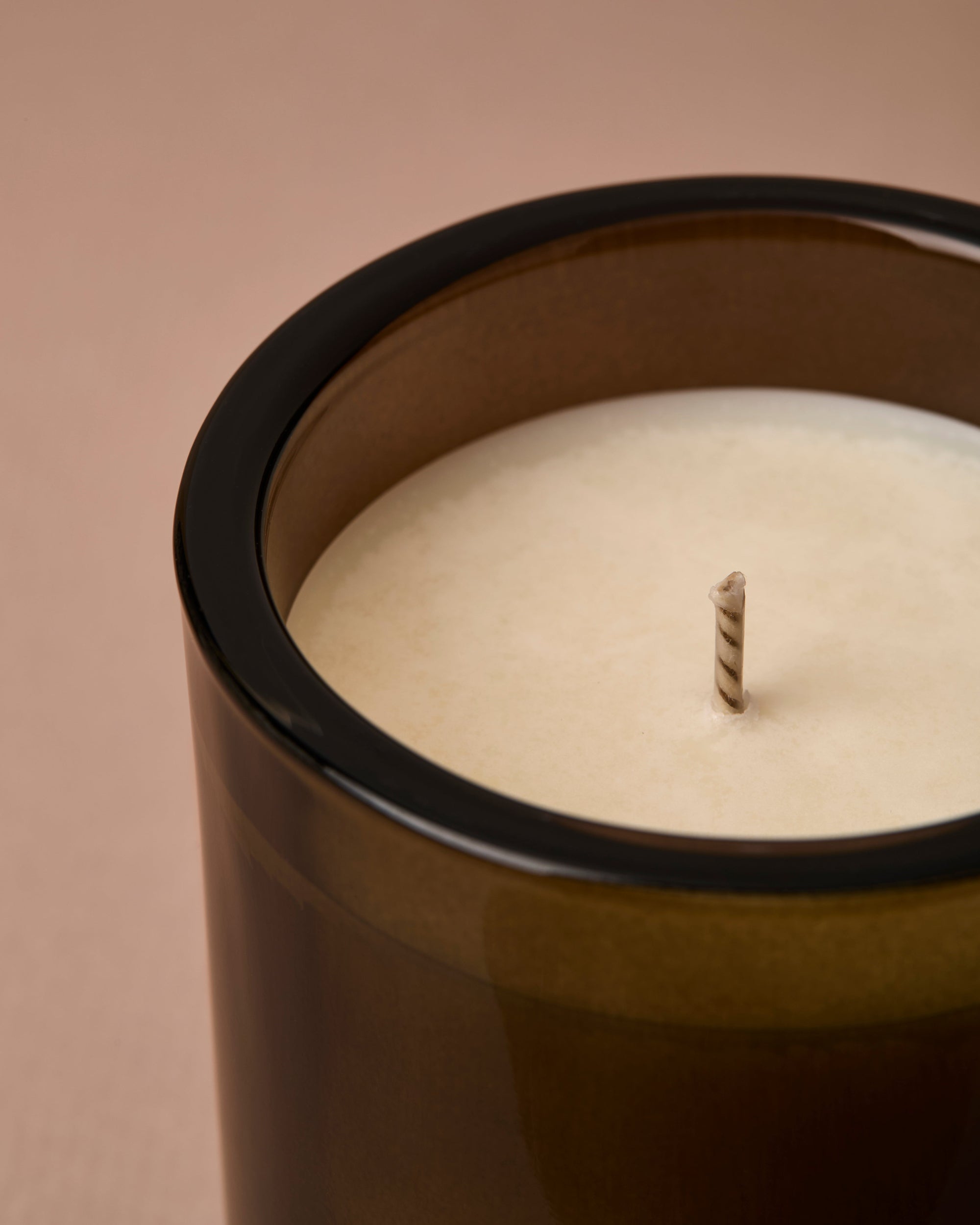 Candle in a green/brown container on a beige background
