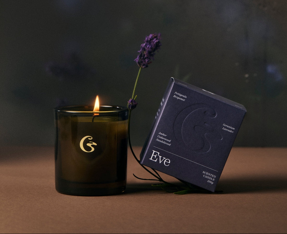 Candle with a lit wick and packaging on a dark background with the name eve