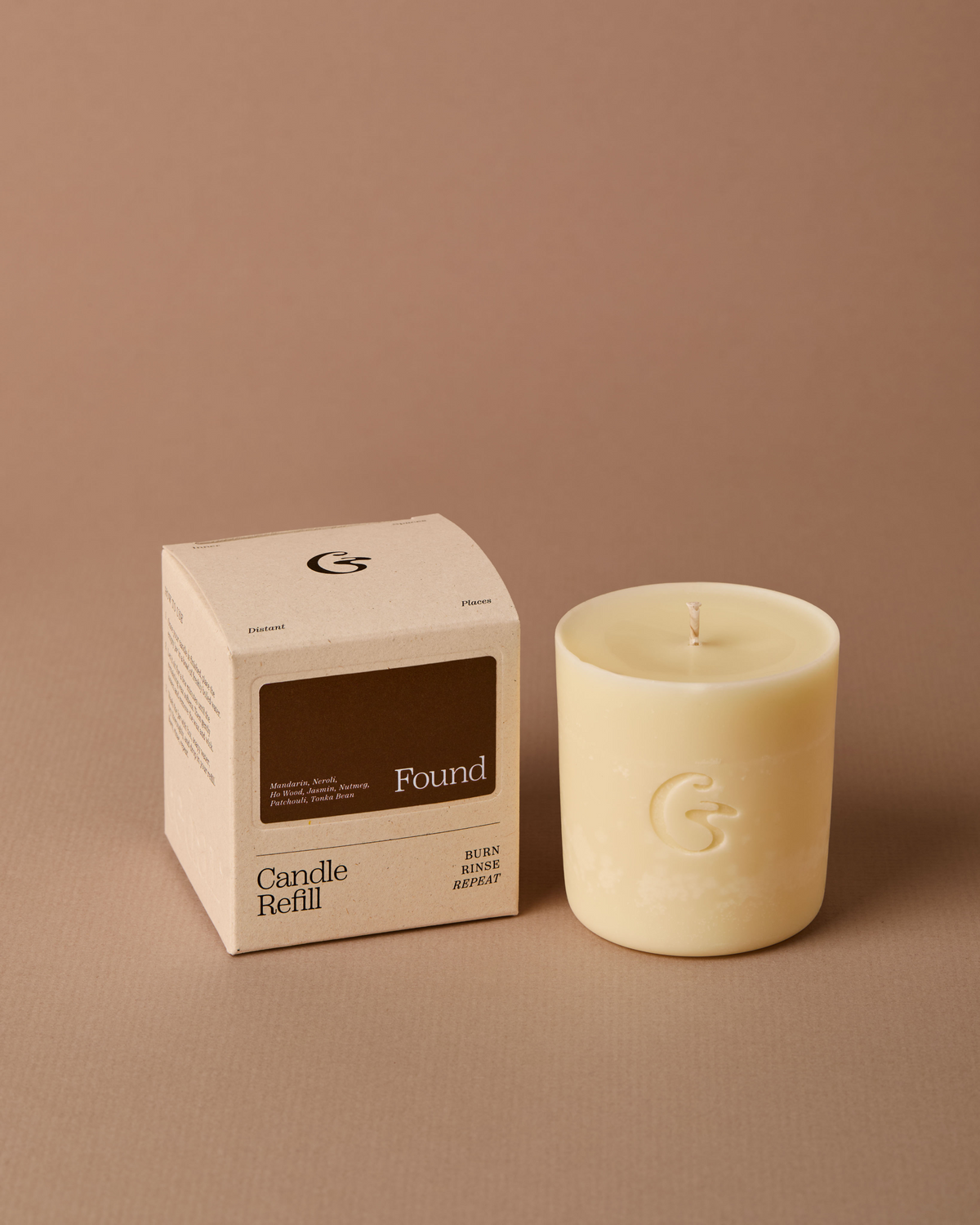 A cream-colored candle refill next to its beige packaging box, which features a dark brown label reading &