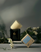 A class candle jar with a wax candle refill balancing on the top. A box on the left which says "nord"