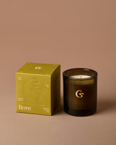 Brown candle with gold logo sat next to a packaging box with the name &