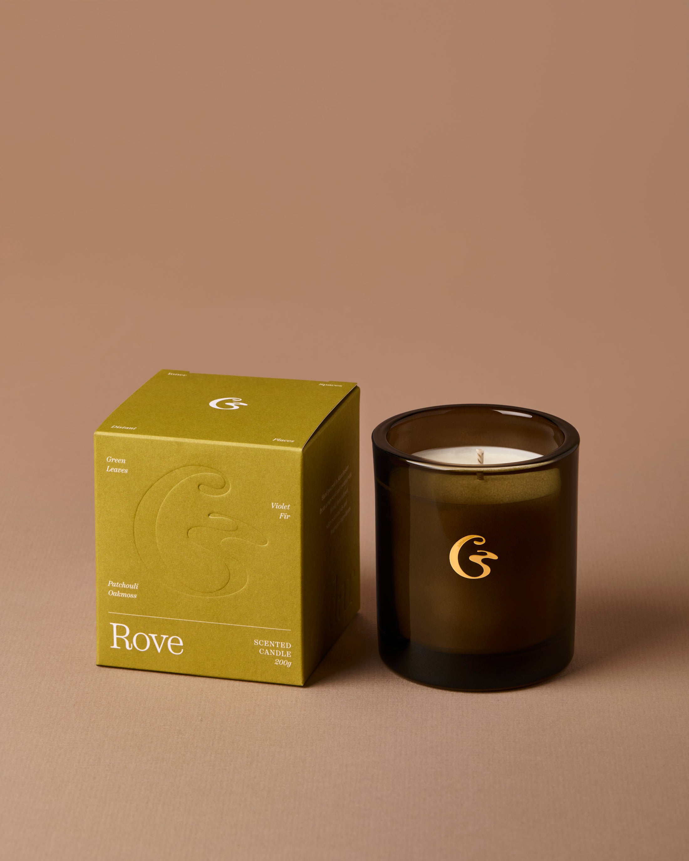 Brown candle with gold logo sat next to a packaging box with the name &