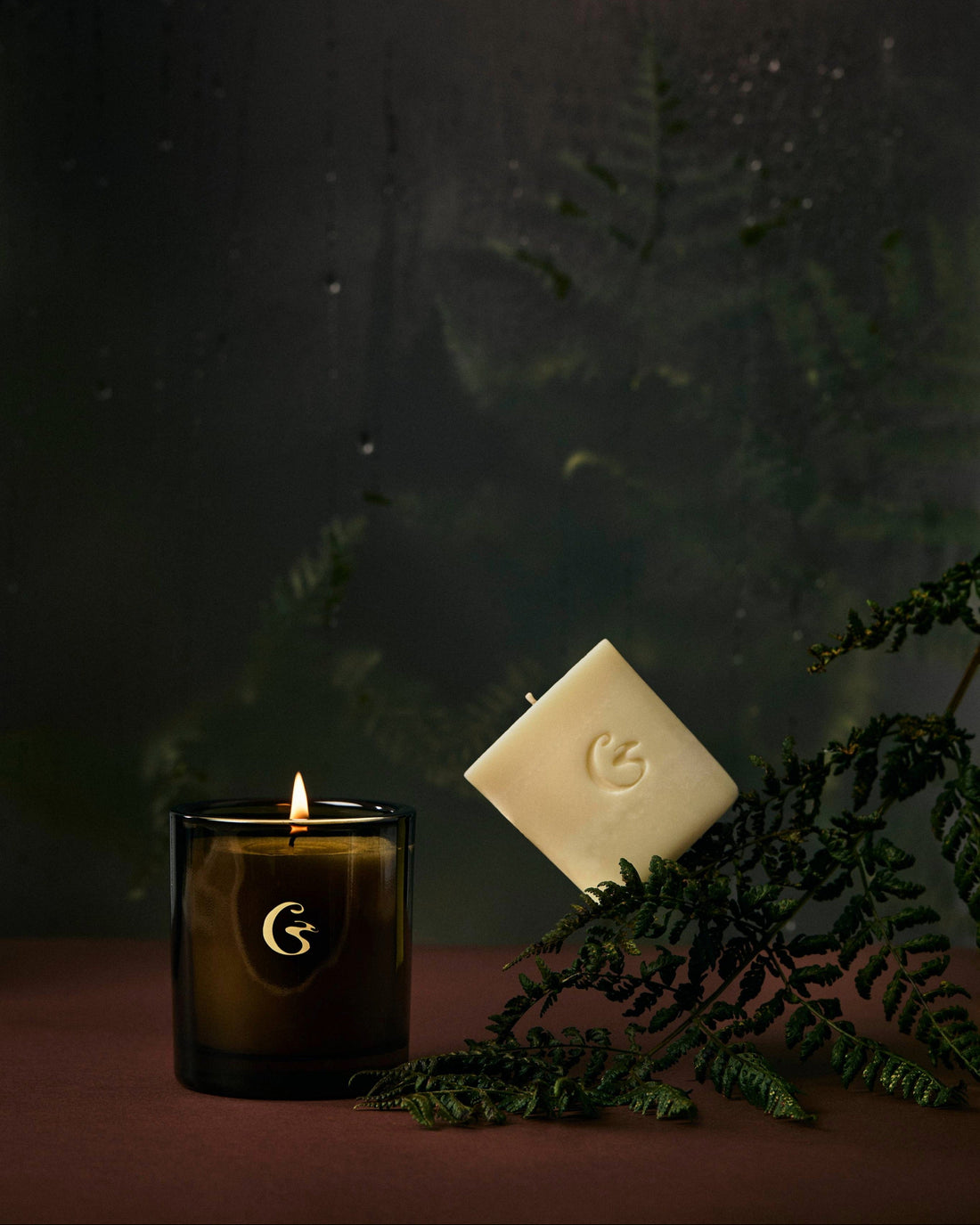 Candle with a wax candle refill and leaves on a dark background