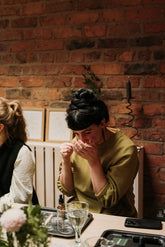 A woman smelling scent strips in a workshop setting. Red brick behind her. 