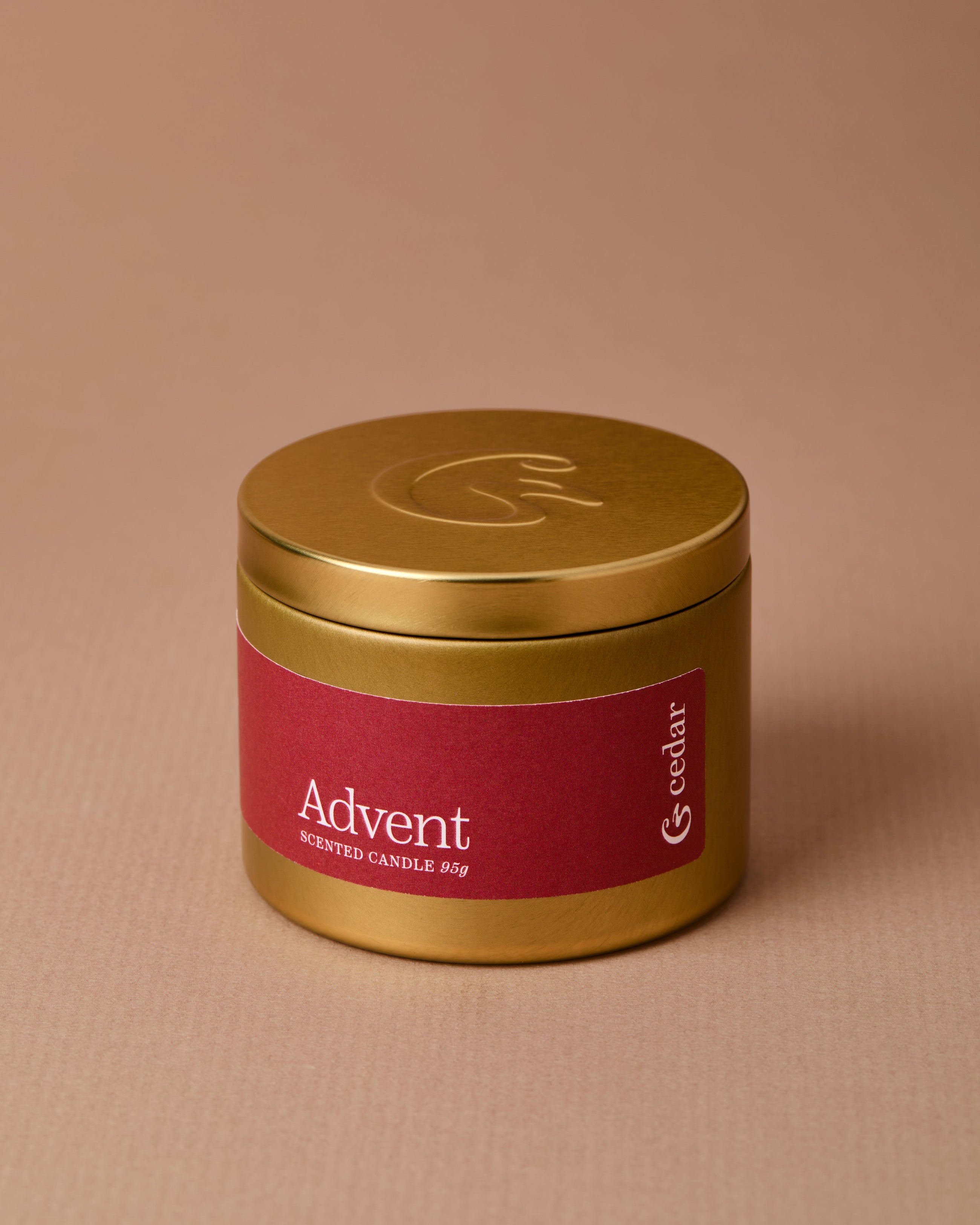Gold tin candle with a red label with the name &